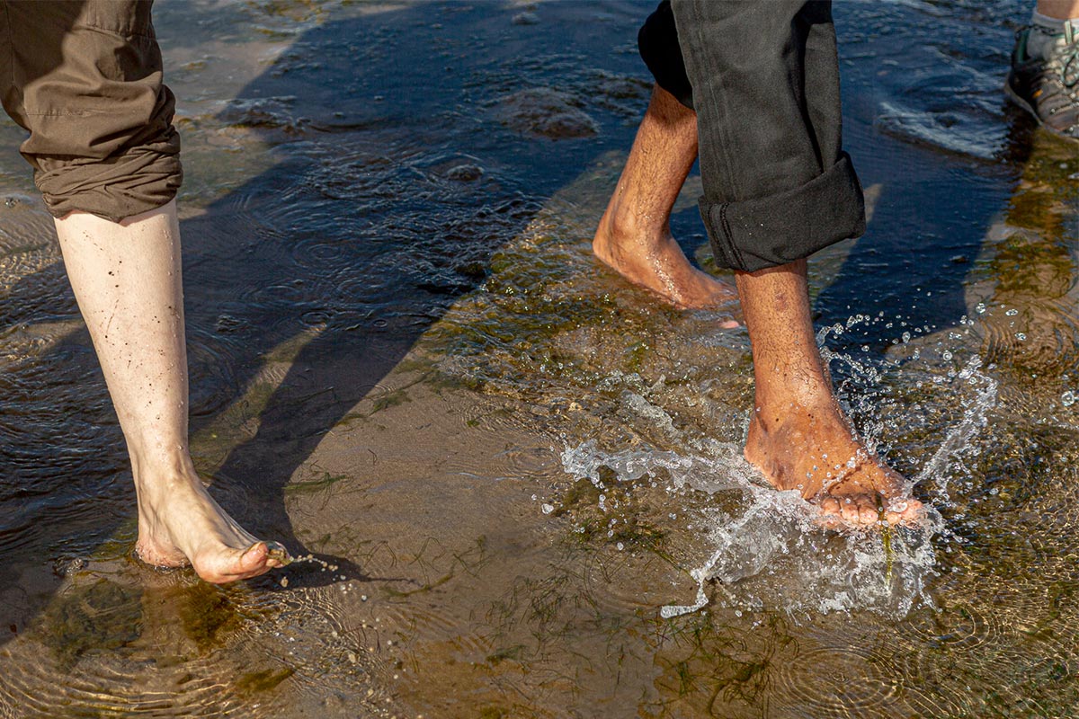 Two people's barefeet splashing in water.