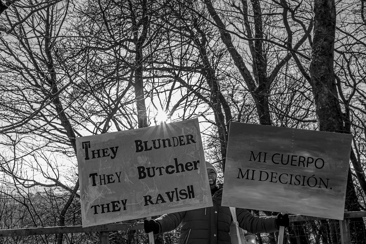 A woman holding two banners in nature.